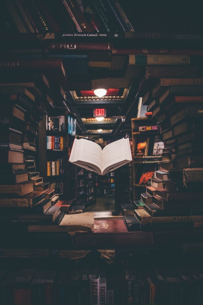 Photo by Jaredd Craig view of floating open book from stacked books in library