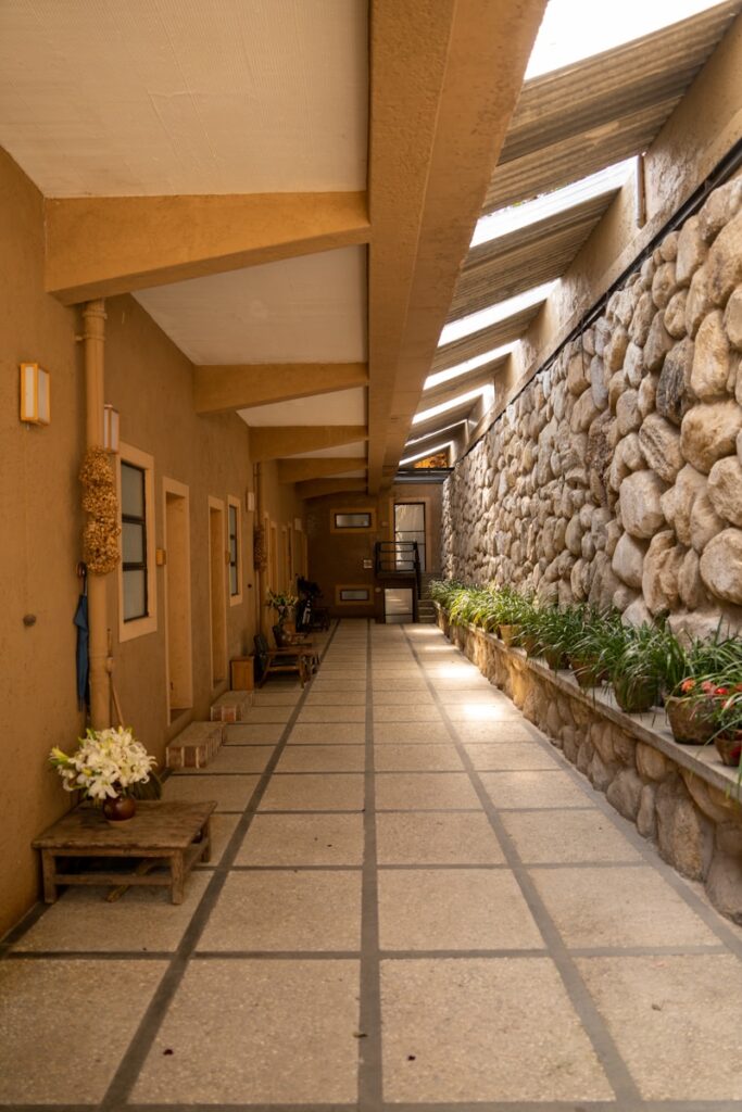 Photo by Yunshuo Qu a long hallway with a stone wall and planters